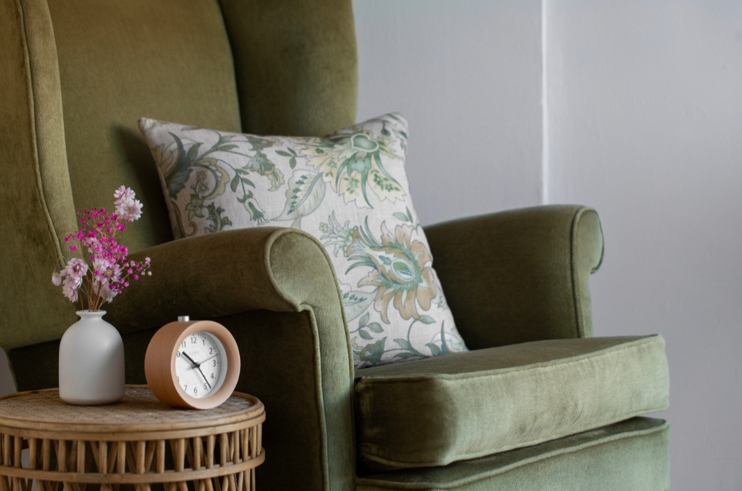 a seat in a therapist office with a plant and a clock on a side table